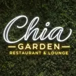 Eine Leuchtreklame mit der Aufschrift „Chia Garden Restaurant & Lounge“ an einer üppig mit grünen Pflanzen bewachsenen Wand.
