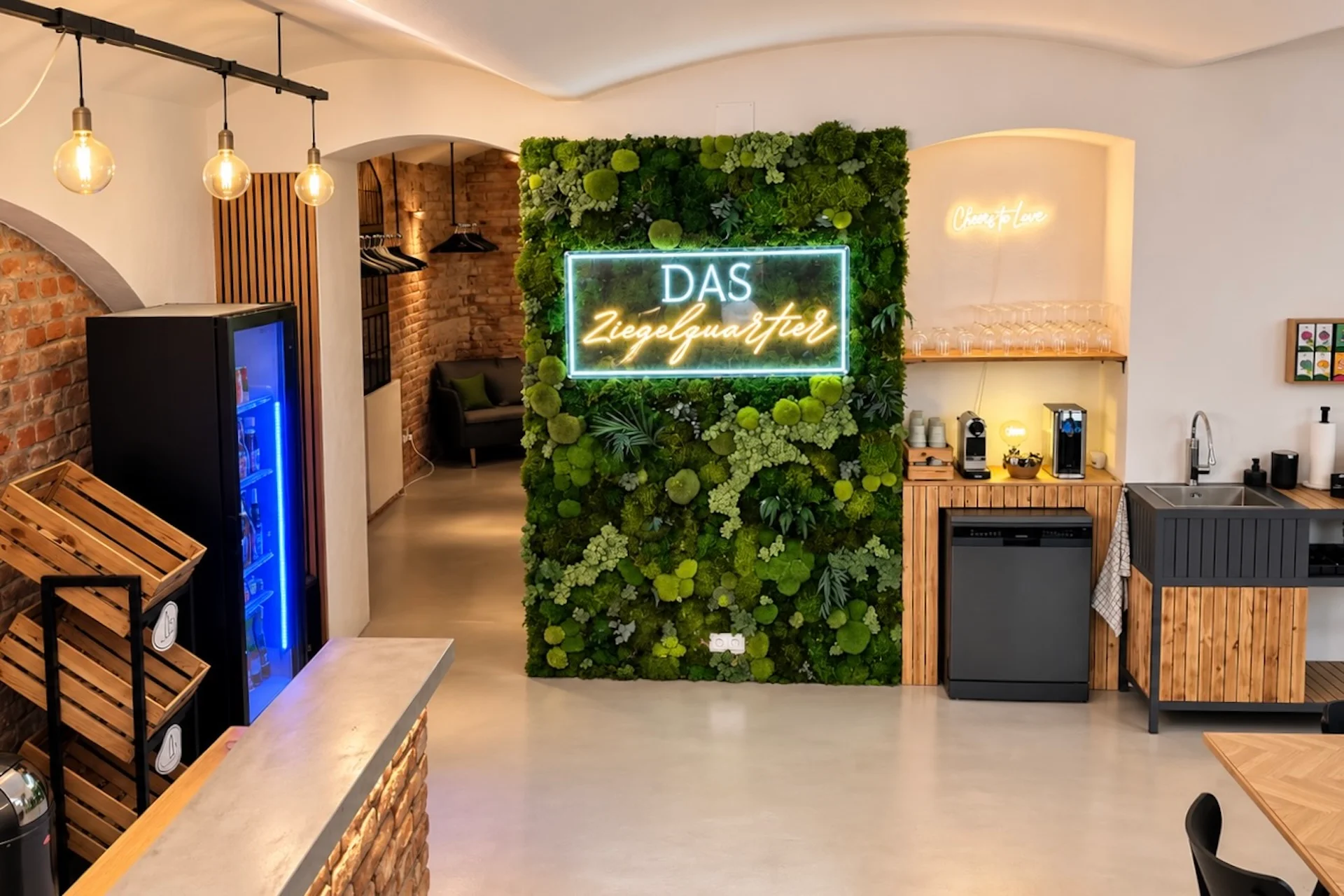 Eine lebende Mooswand mit einer Leuchtreklame, auf der DAS Ziegelquartier steht, in einem modernen Café.