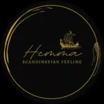 Ein rundes schwarzes Logo mit goldenen Akzenten, das ein stilisiertes Wikingerschiff über dem kursiven Wort Hemma und dem Satz SCANDINAVIAN FEELING in Großbuchstaben zeigt.