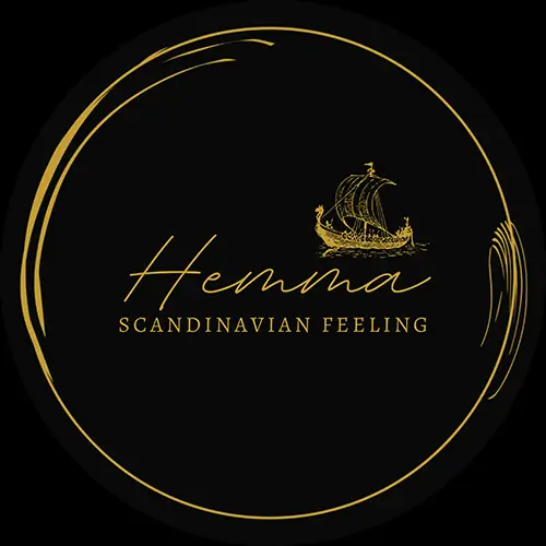 Ein rundes schwarzes Logo mit goldenen Akzenten, das ein stilisiertes Wikingerschiff über dem kursiven Wort Hemma und dem Satz SCANDINAVIAN FEELING in Großbuchstaben zeigt.