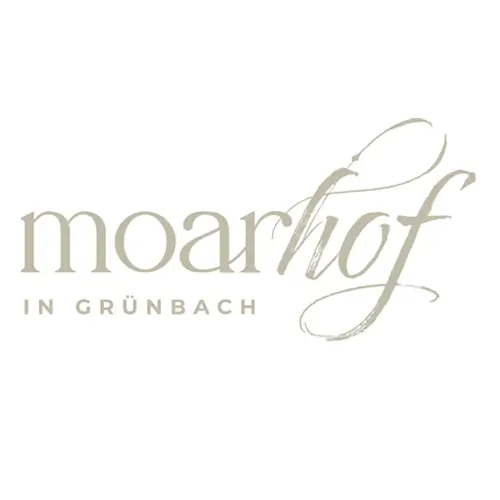 Logo mit dem Schriftzug moarhof in großer, eleganter Schrift und darunter IN GRÜNBACH in kleineren Großbuchstaben, alles in zartem Beige auf weißem Hintergrund.