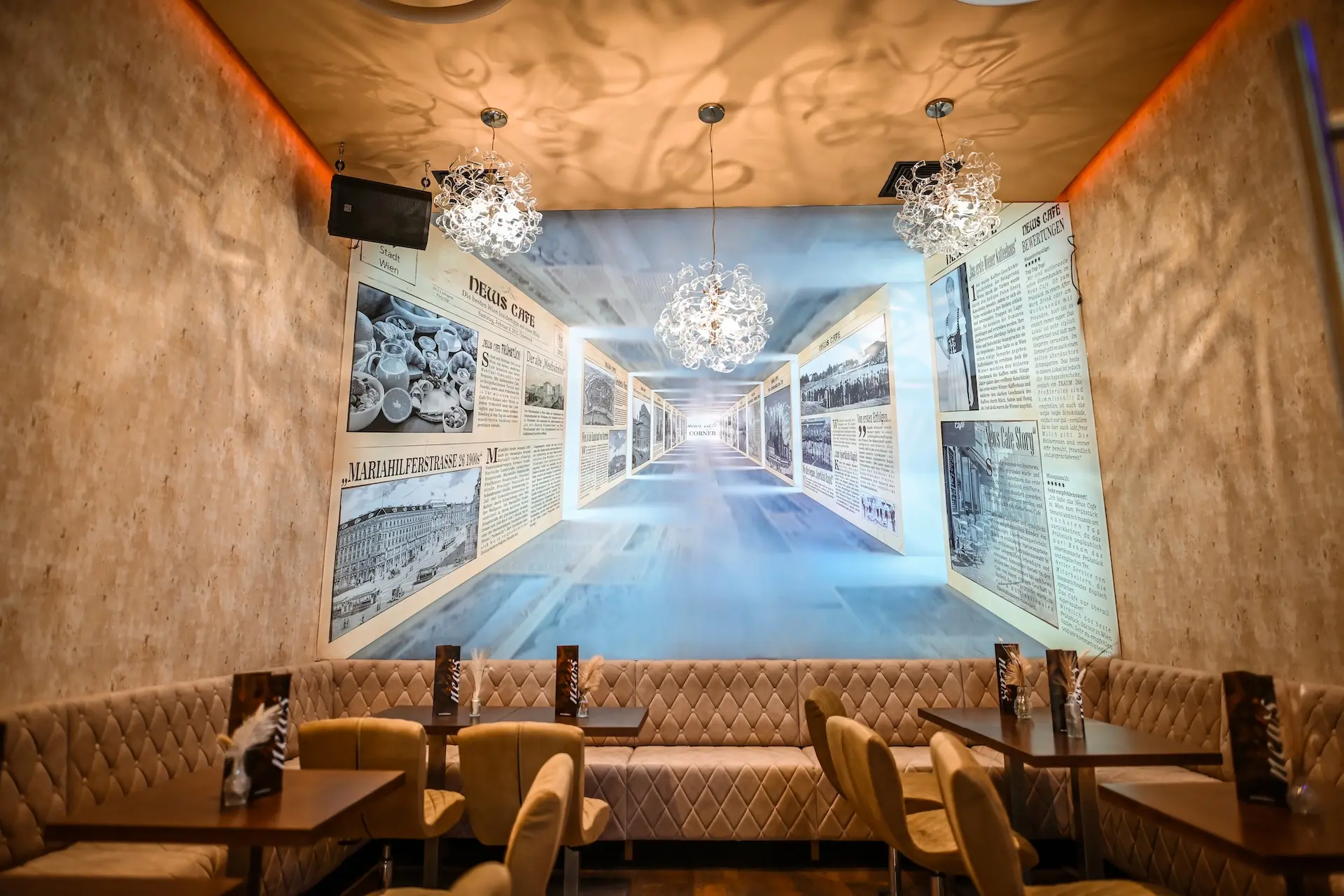 Ein stilvolles Restaurantinterieur mit gepolsterten beigen Sitzen, modernen Stühlen, dunklen Holztischen und verzierten Hängelampen. An der Rückwand befindet sich ein großes Wandgemälde, das an alte Zeitungen erinnert, und ein Flur mit Fluchtpunkt.