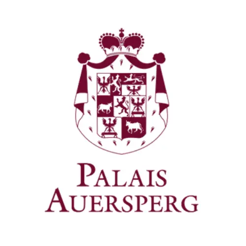 Kastanienbraunes heraldisches Wappen mit Krone, Tieren und Symbolen über dem Text "Palais Auersperg" in eleganten Großbuchstaben auf weißem Grund.