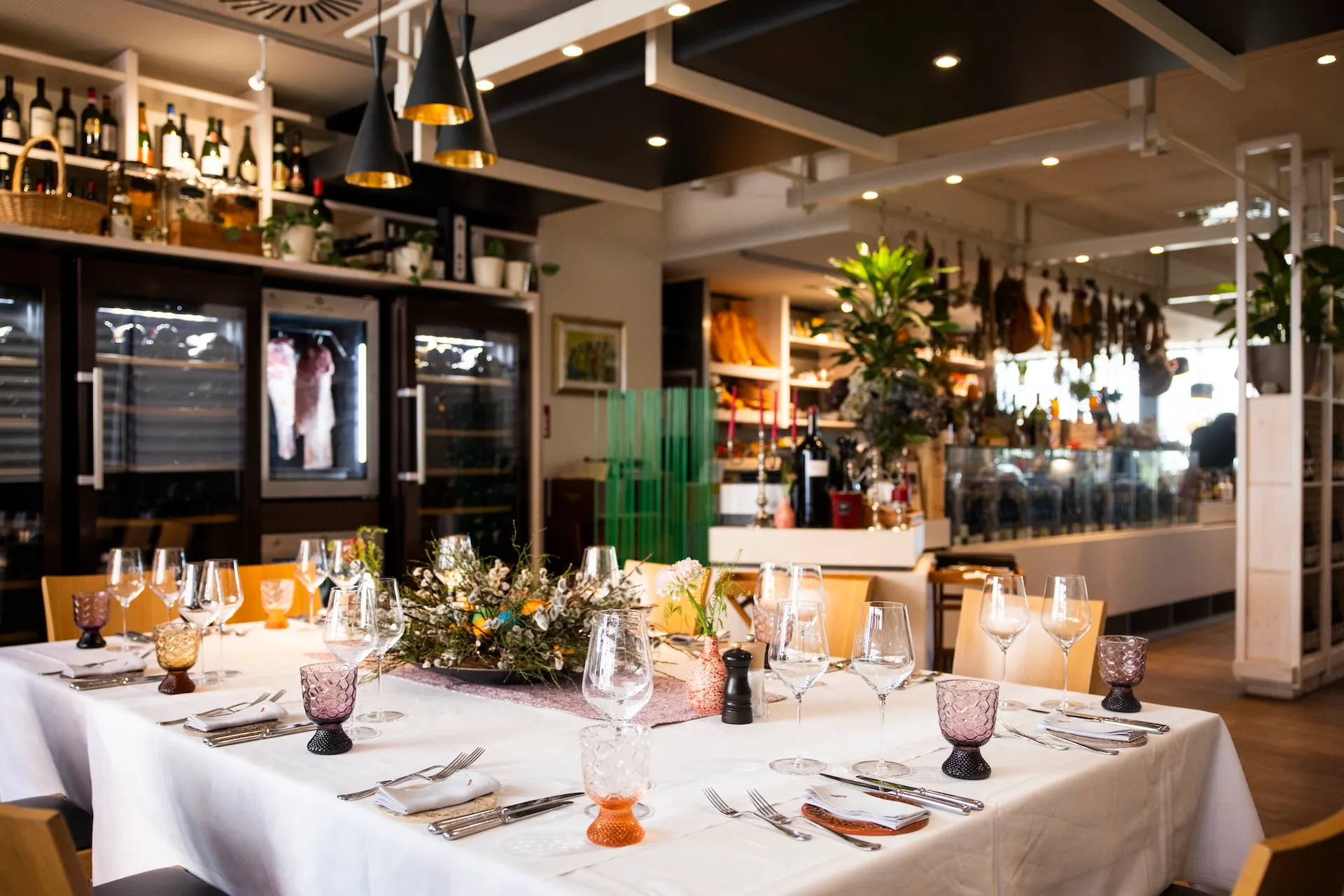 ROSSO di ACQUA e SOLE Ein festlich gedeckter Esstisch mit weißer Tischwäsche, Weingläsern und Besteck in einem Restaurant.
