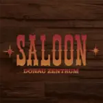 Der Text lautet SALoon in großen westlichen Buchstaben und DONAU ZENTRUM in kleinerer Schrift darunter, auf einem dunklen Holzhintergrund mit zwei Sterngrafiken auf jeder Seite.