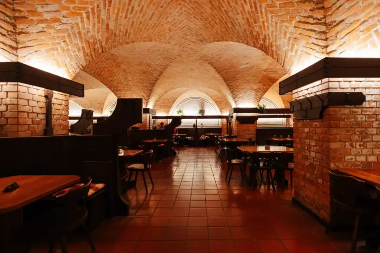 Innenansicht eines Restaurants mit gewölbten Ziegeldecken, Fliesenböden und dunklen Holzsitznischen.