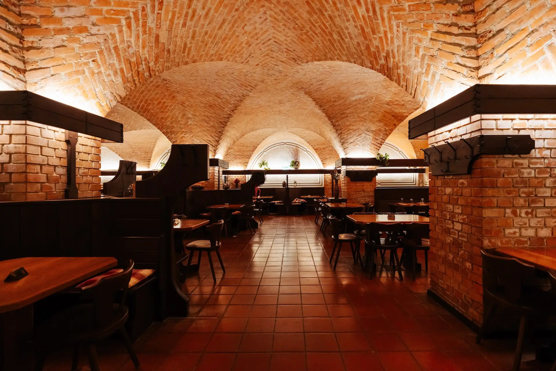 Innenansicht eines Restaurants mit gewölbten Ziegeldecken, Fliesenböden und dunklen Holzsitznischen.