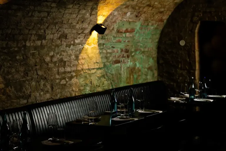 Das schummrig beleuchtete Restaurant mit seinen gewölbten Backsteinwänden, den schwarzen, gepolsterten Sitzen und den dunklen, mit Gläsern und Flaschen bestückten Tischen schafft eine gemütliche und intime Atmosphäre.