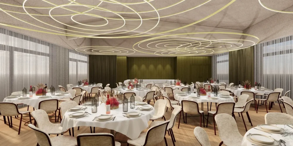 Neuer Strand Ein moderner Bankettsaal mit runden Tischen, die für eine Veranstaltung gedeckt sind, mit weißen Tischtüchern, eleganten Gedecken und blumigen Tafelaufsätzen. Einzigartige spiralförmige Deckenleuchten und neutralfarbene Stühle vervollständigen die stilvolle Einrichtung.