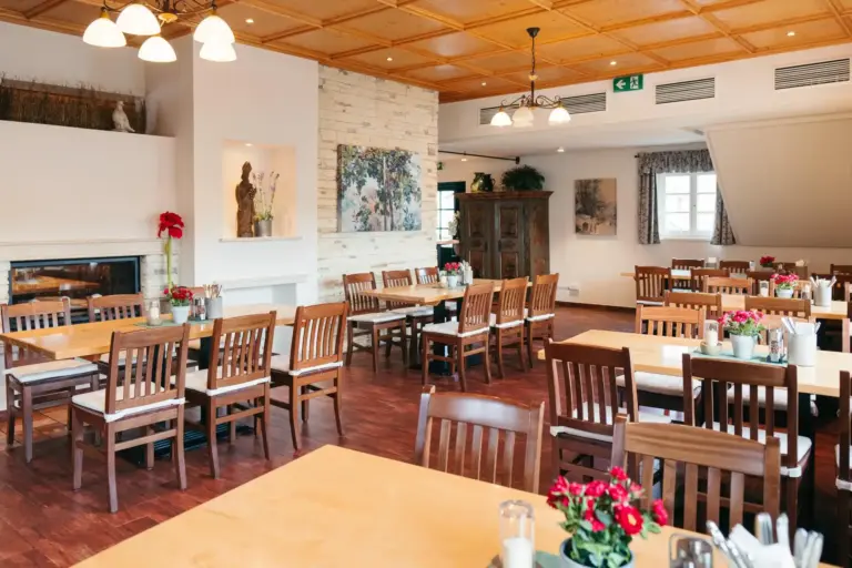 Pfiff Ein geräumiger, heller Restaurantbereich mit Holztischen und -stühlen, geschmückt mit Gemälden, Pflanzen und Blumen auf den Tischen, mit einer hellen Holzdecke und Parkettböden.